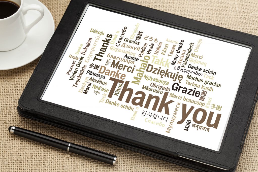 thank you in different languages - word cloud on a  digital tablet with a cup of coffee